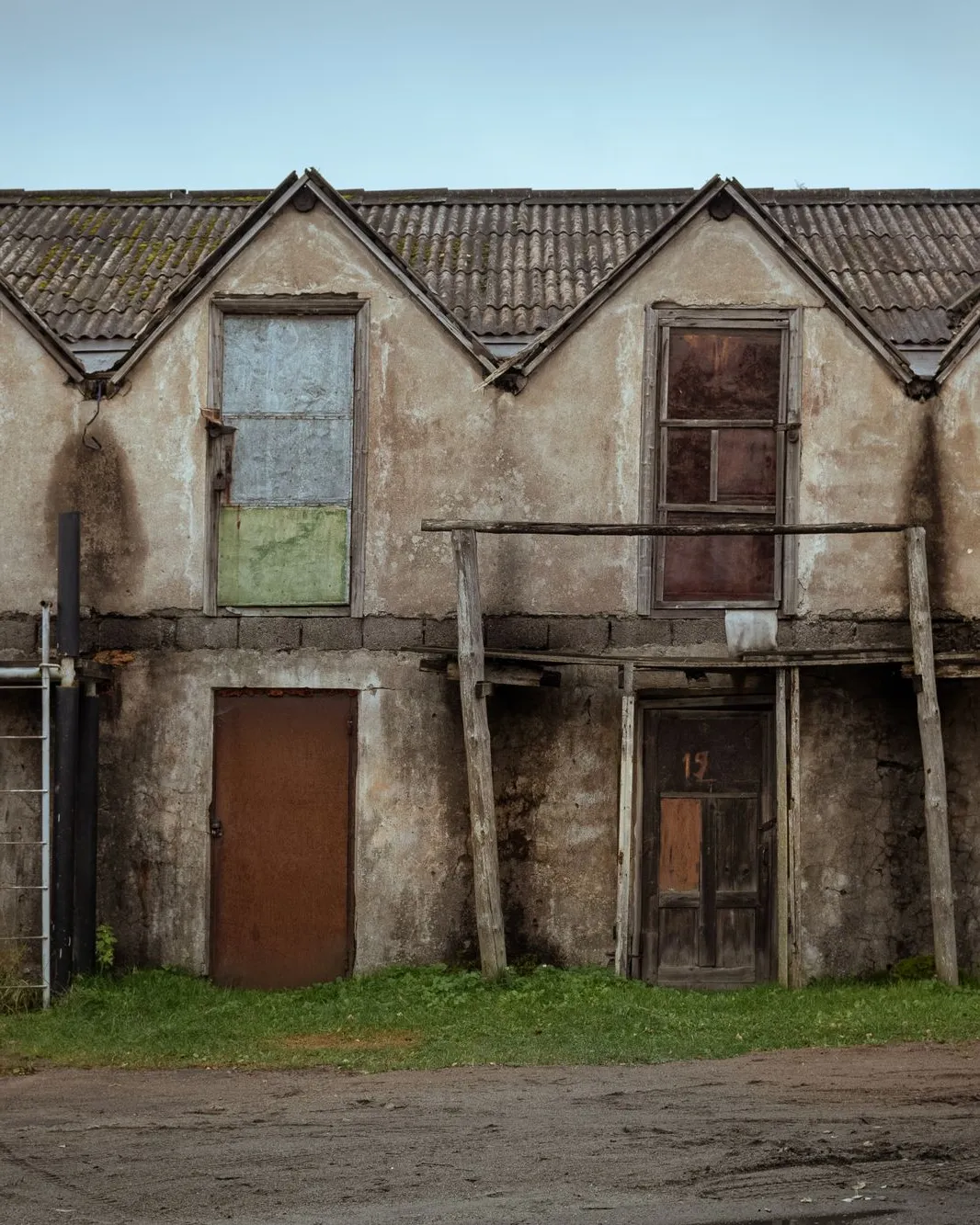 Maison ancienne délabrée aux volets et portes en bois abîmés, enduit écaillé