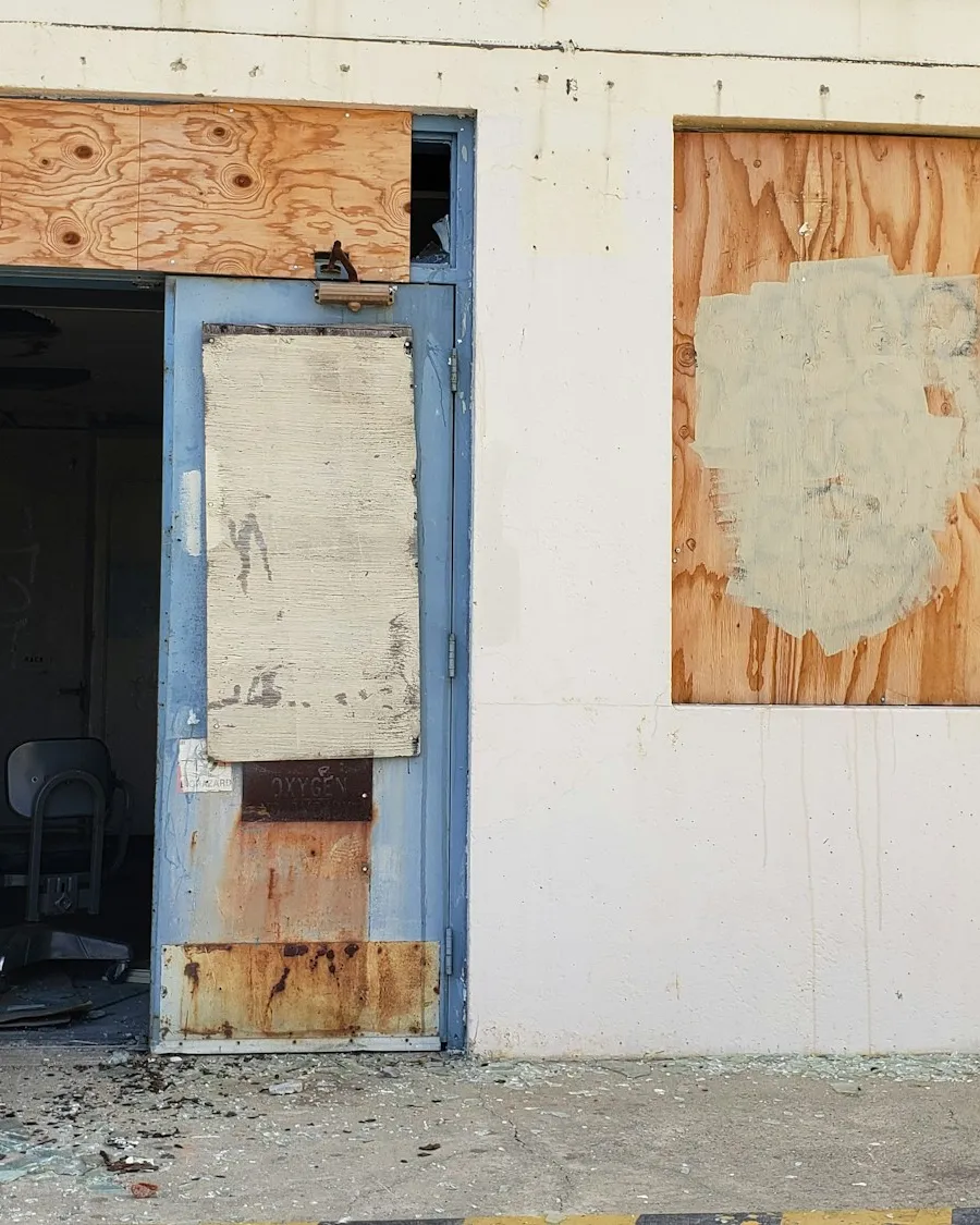 Rez-de-chaussée d'un bâtiment dégradé aux portes et fenêtres condamnées par des planches